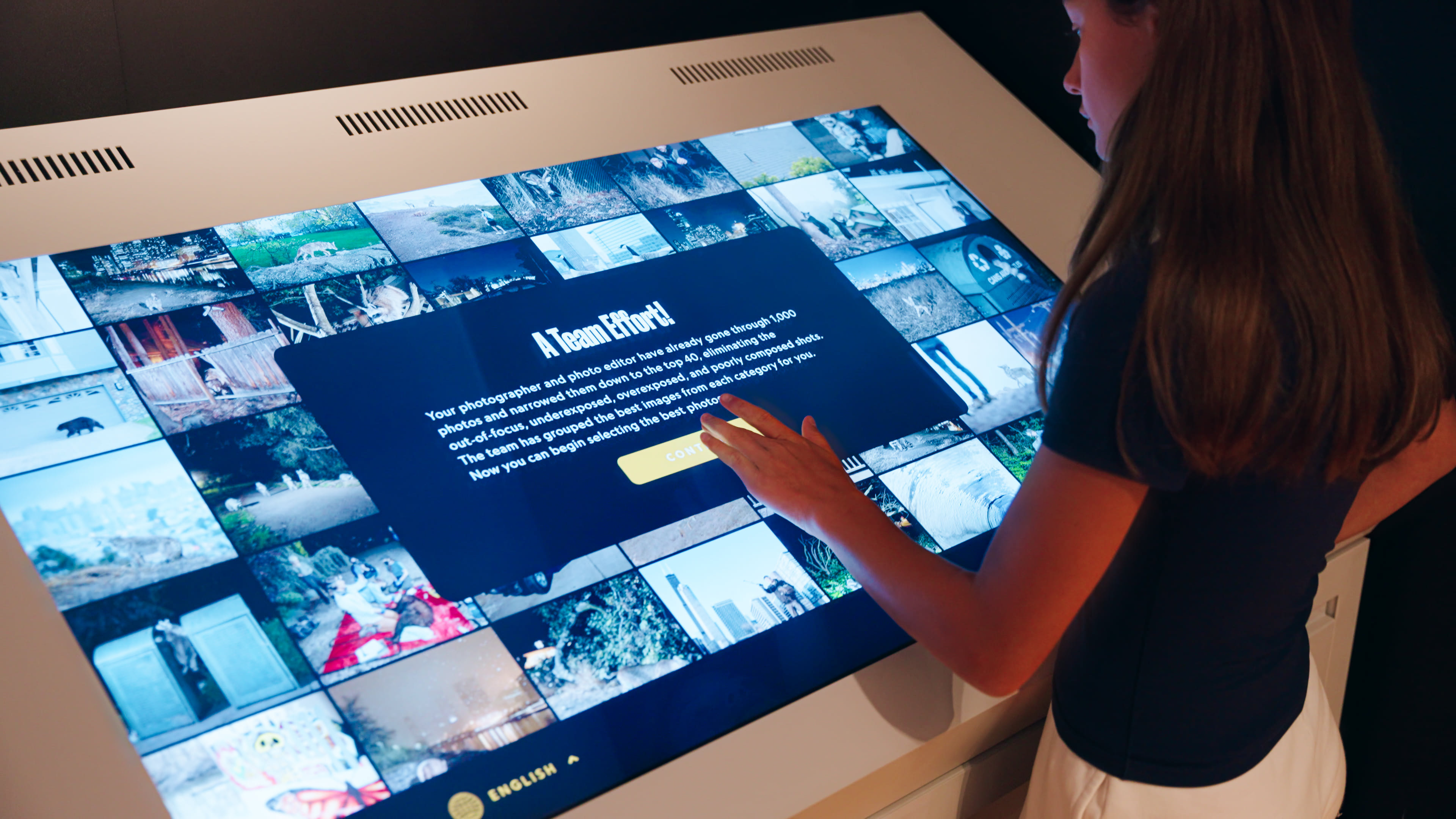 Visitor using the Photo Editor touchscreen with a grid of assignment photographs